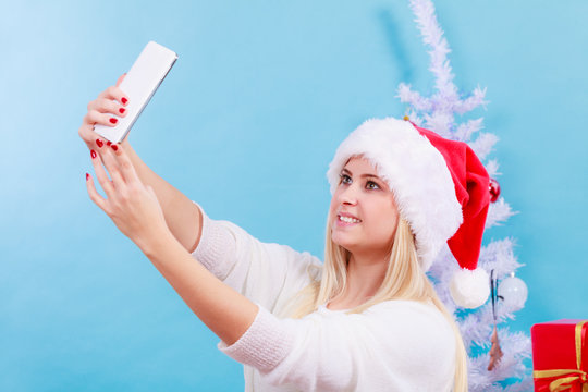 Girl in santa hat taking picture of herself using phone