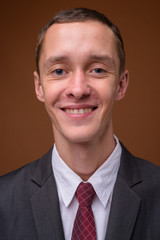 Studio shot of young businessman against brown background