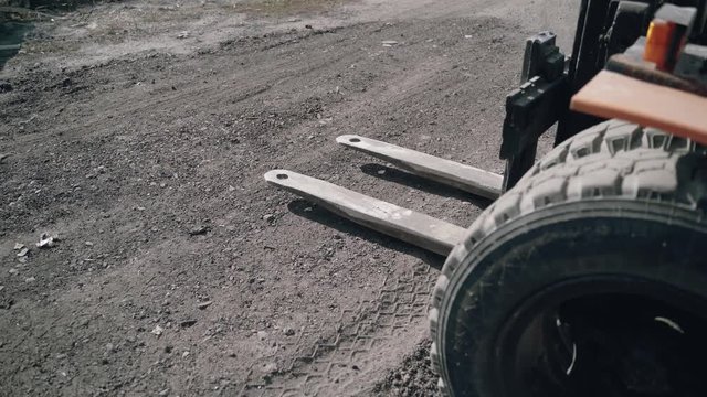 a forklift is approaching the pallet with bricks and lifting it to moving to another place in the street.