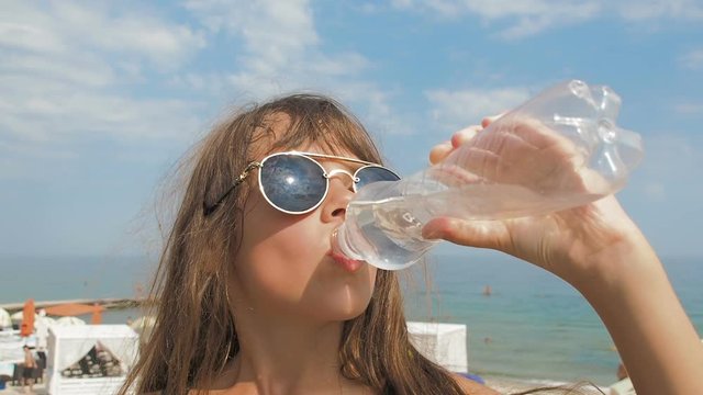 A child on the beach drinks water.