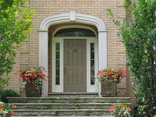 Fototapeta na wymiar front door with sidelights and transom window, on brick house with stone steps