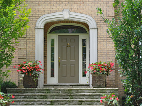 front door with sidelights and transom window, on brick house with stone steps
