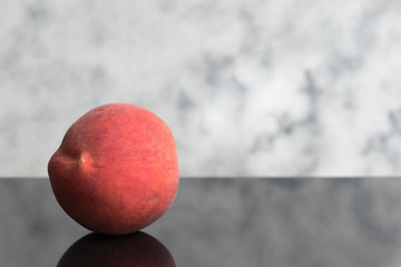 Ripe peach fruit isolated on dark granite surface with clear marble background