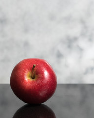Isolated red mcintosh apple on dark granite surface with clear marble background