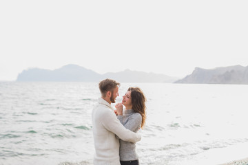Man and woman in love enjoying together near sea, running by the beach, laughing, kissing and hugging