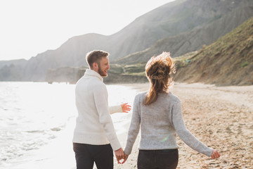 Man and woman in love enjoying together near sea, running by the beach, laughing, kissing and hugging