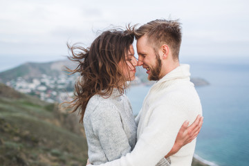 Close-up portrait of couple with wind in hair, hugging and happy together. Both in sweaters