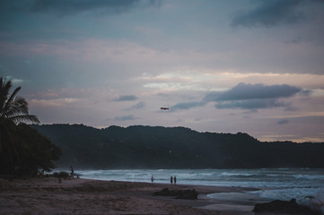 Fototapeta na wymiar Cloudy peaceful sunset on the long beach of Playa Carmen in Santa Teresa, Costa Rica