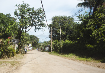 Fototapeta premium Dusty main road through the small town of Santa Teresa, on the pacific coast of the Nicoya peninsula, Costa Rica