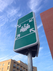 Meeting point sign pole over blue sky close to hospital