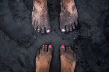 Above view of young couple's feet as they stand face-to-face on volcanic black sand on Playa Negra in Puero Viejo, Costa Rica - Powered by Adobe