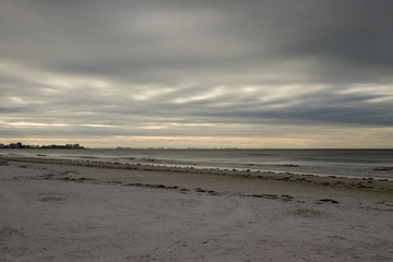 Sunrise along beachfront on stormy morning along Fort Myers Beach on Estero Island in Florida. View of Fort Meyers in background.