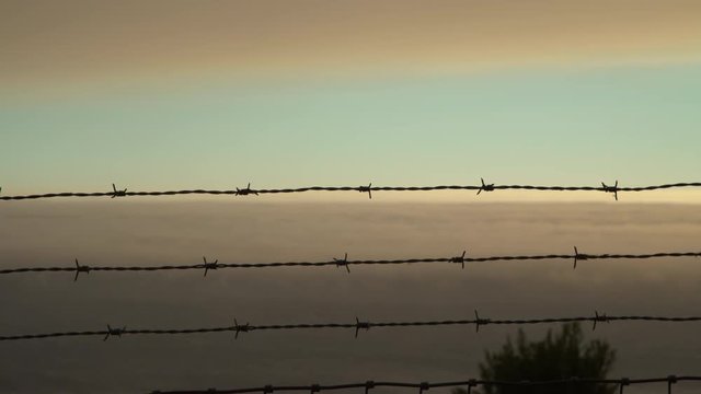 Thick rolling clouds over the ocean in Big Sur, silhouetted fence in foreground