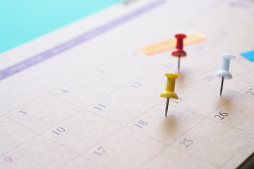 close up of pin on calendar on the green background, planning for business meeting or travel planning concept