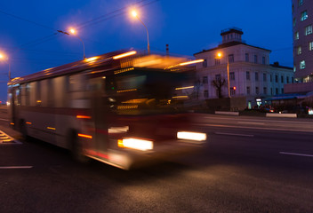 Fototapeta premium The motion of a blurred bus on the avenue in the evening.