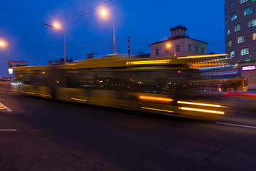 Obraz premium The motion of a blurred bus on the avenue in the evening.