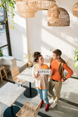 Helpful wife. Dark-haired handsome man looking at his wife helping him with their business