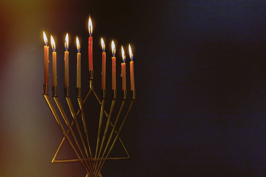 Menorah with colorful candles for Hanukkah on light blue background, close up