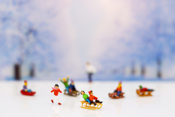 Miniature people: Childrens playing fun with snow slider.