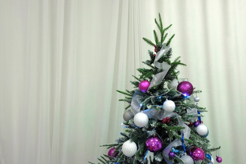 Theme of happy new year. The top of the Christmas tree hung with toys against the backdrop of curtains. Copyspace.