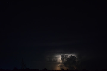 Lightning Storm on the horizon. The clouds are illuminated by a lightning strike. Taken on a summer night in rural midwest state of Michigan.