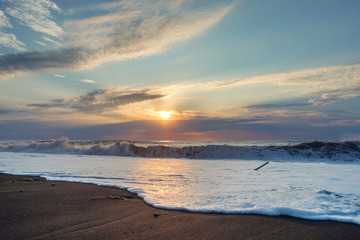 Foamy wave at the sunset sandy beach