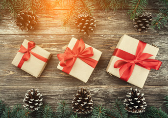 Old wooden background with fir branches adorned with cones. Space for text. Christmas card. Top view. Xmas gifts. Light effect.