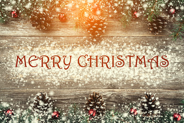 Old wood background with fir branches adorned with baubles and cones. Space for text. Christmas card. Top view. Xmas. Effect of snow and light.