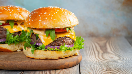 Two fresh homemade burgers with fried potatoes on a wooden table. With copy space