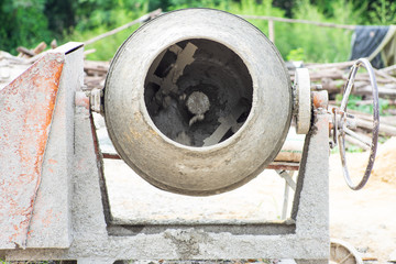 Closeup picture of dirty concrete mixer working at the construction site