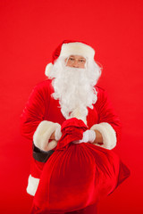Portrait of Santa Claus with huge red sack looking at camera