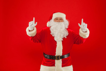 Santa Claus pointing in blank a place, red background.