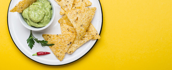 Traditional Latinamerican Guacamole With Corn Chips Nachos on yellow background. Banner format