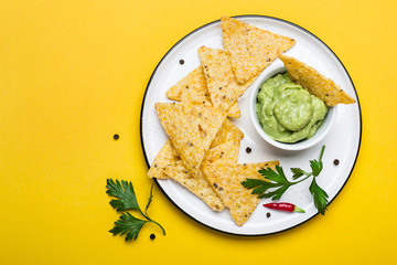 Traditional Latinamerican Guacamole With Corn Chips Nachos on yellow background