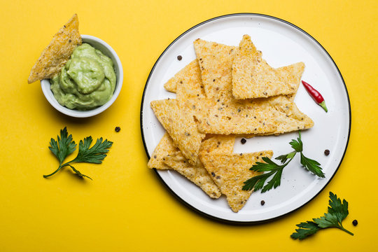 Traditional Mexican food Guacamole With Corn Chips on yellow background