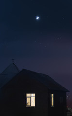 A house during a starry night with moon above it.