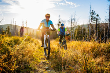 Cycling woman and man at Beskidy mountains autumn forest landscape. Couple riding MTB enduro track....