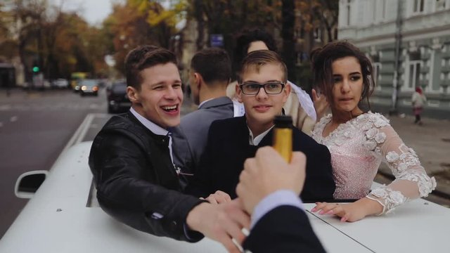 A group of young people traveling in a limousine and celebrate, drink alcohol