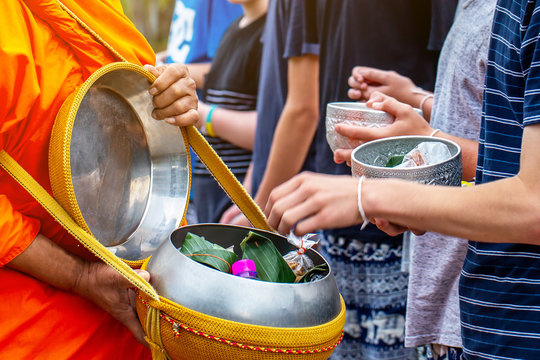 People are making merit by offering food and water into the monk alm bowl in the morning , buddhist tradition. 