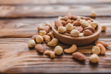 Wooden bowl with mixed nuts ontable. Healthy food and snack. Walnut, pistachios, almonds, hazelnuts and cashews.