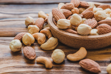 Wooden bowl with mixed nuts ontable. Healthy food and snack. Walnut, pistachios, almonds, hazelnuts and cashews.
