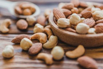 Wooden bowl with mixed nuts ontable. Healthy food and snack. Walnut, pistachios, almonds, hazelnuts and cashews.