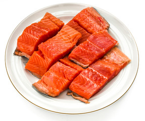 Trout cut in pieces in a white round plate. Red fish. White isolated.