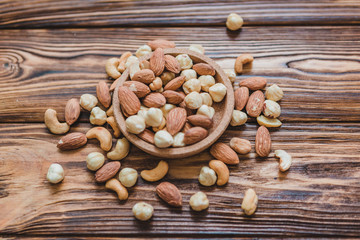 Wooden bowl with mixed nuts ontable. Healthy food and snack. Walnut, pistachios, almonds, hazelnuts and cashews.