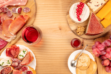 Charcuterie Tasting. A photo of many different sausages and hams, lunch meats, and a cheese platter, shot from above on a rustic background with a glass of red wine and copy space © laplateresca