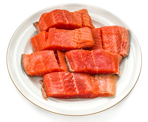 Trout cut in pieces in a white round plate. Red fish. White isolated.
