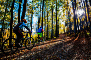 Obraz premium Cycling woman and man at Beskidy mountains autumn forest landscape. Couple riding MTB enduro track. Outdoor sport activity.