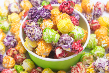 paper cup with caramel popcorn on the background of multi-colored corn