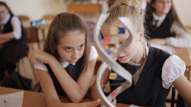 high school students in school uniform study the structure of DNA in a biology class