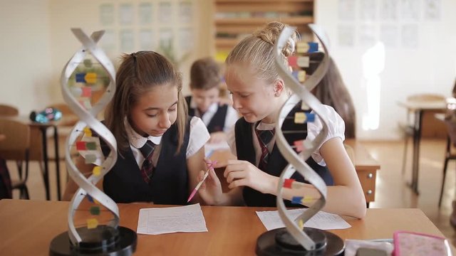 high school students in school uniform study the structure of DNA in a biology class